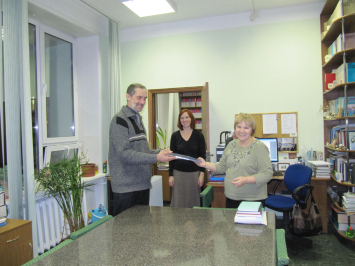 Представитель ОАО ИСС Николай Николаевич Шумаков вручает книгу сотруднику библиотеки Ирине Юрьевне Павловской